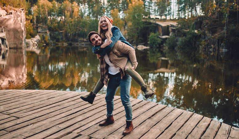 Young couple of tourists are exploring new places. Attractive young woman and handsome bearded man are spending time and having fun together on nature.